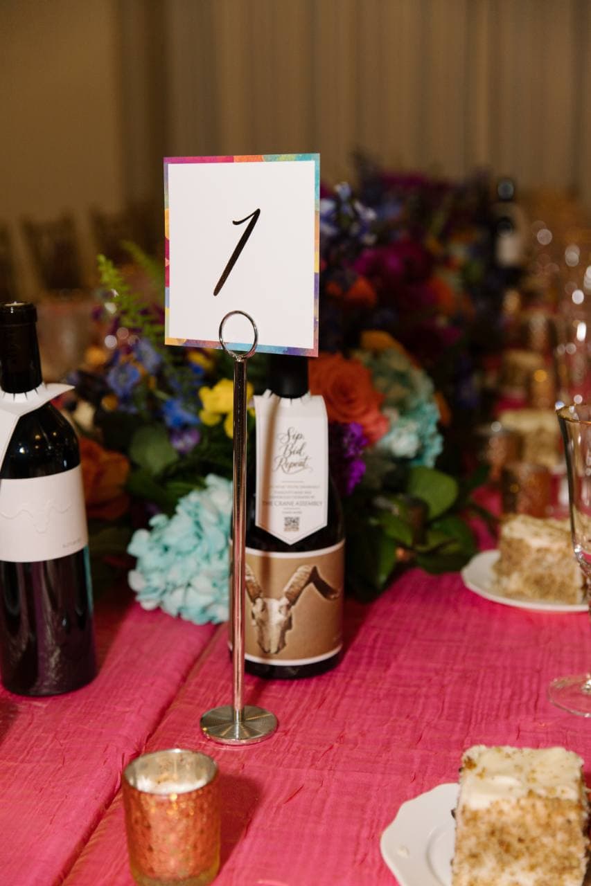 Printed table-number card with a watercolor border in a metal table stand