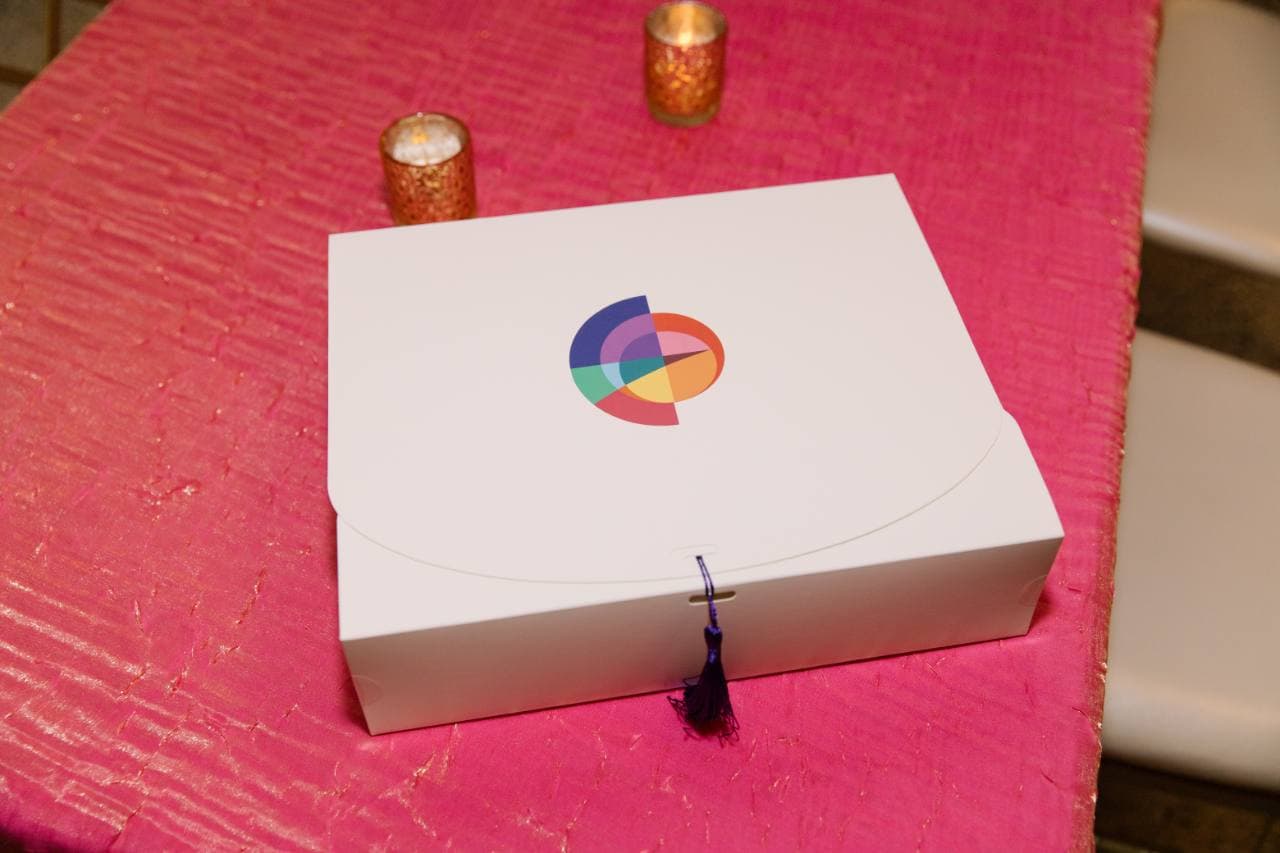 Closed white take-home box with the colorful Gala of Hope logo on its lid